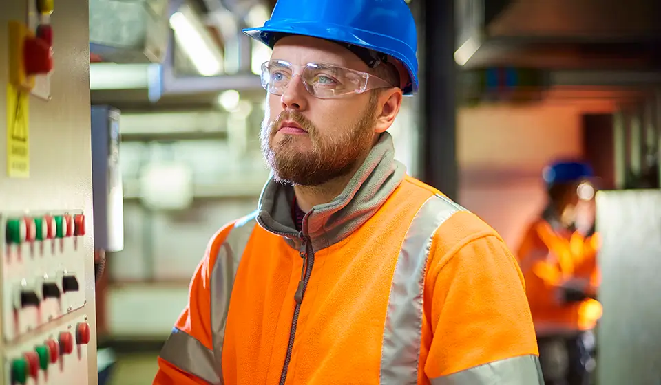Photo of a male factory worker in a hard hat and safety glasses